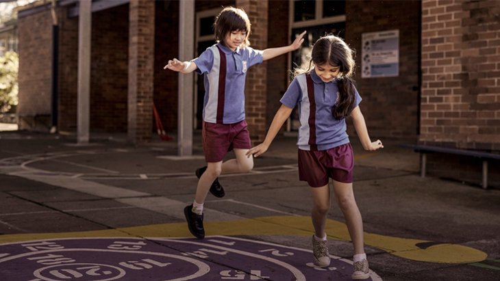 EDMSWS Two students in uniform playing in their school playground.
