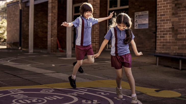 Two students in uniform playing in their school playground.